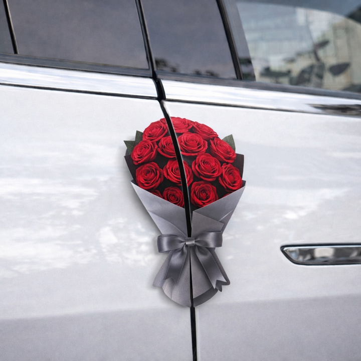 Bouquet of red roses with a silver bow attached to a car door.